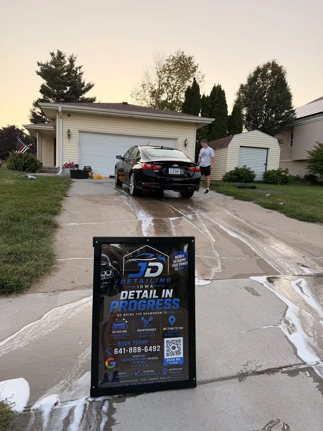 Detail in progress sign set up in a driveway next to a freshly washed SUV